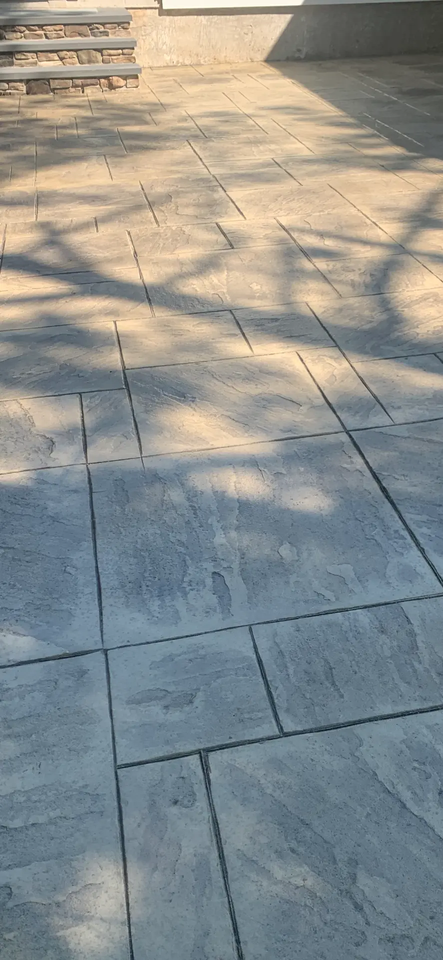 Large slate stamped concrete patio with stone steps