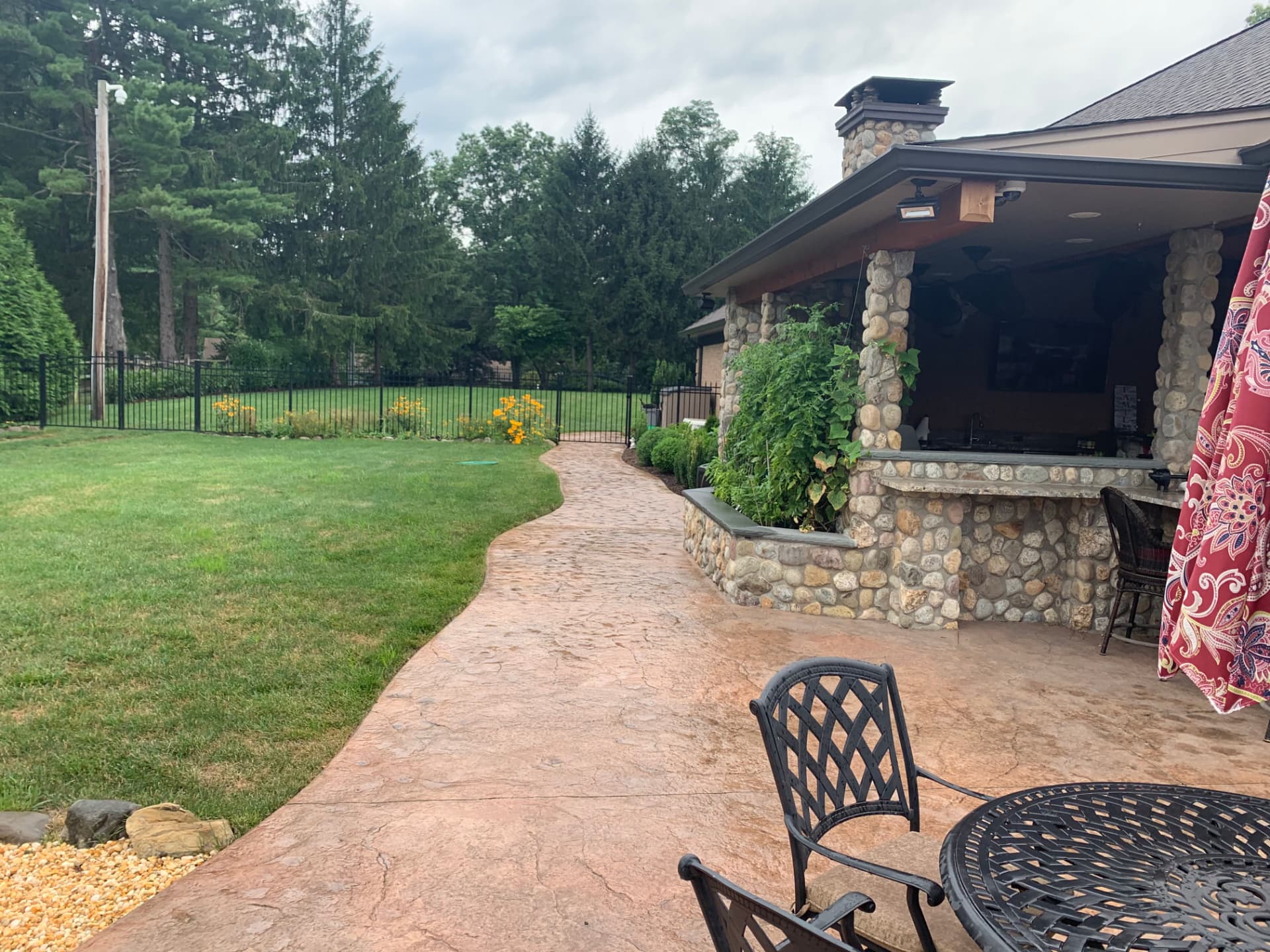 Curved stamped concrete walkway alongside a stone outdoor bar