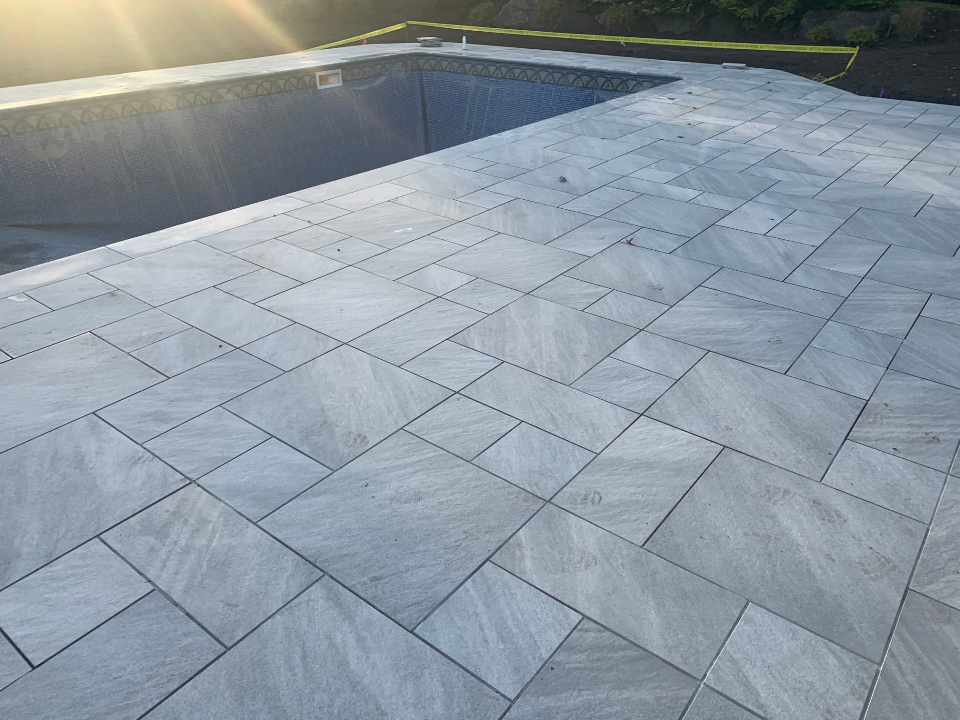 Large gray stone paver pool deck at sunset