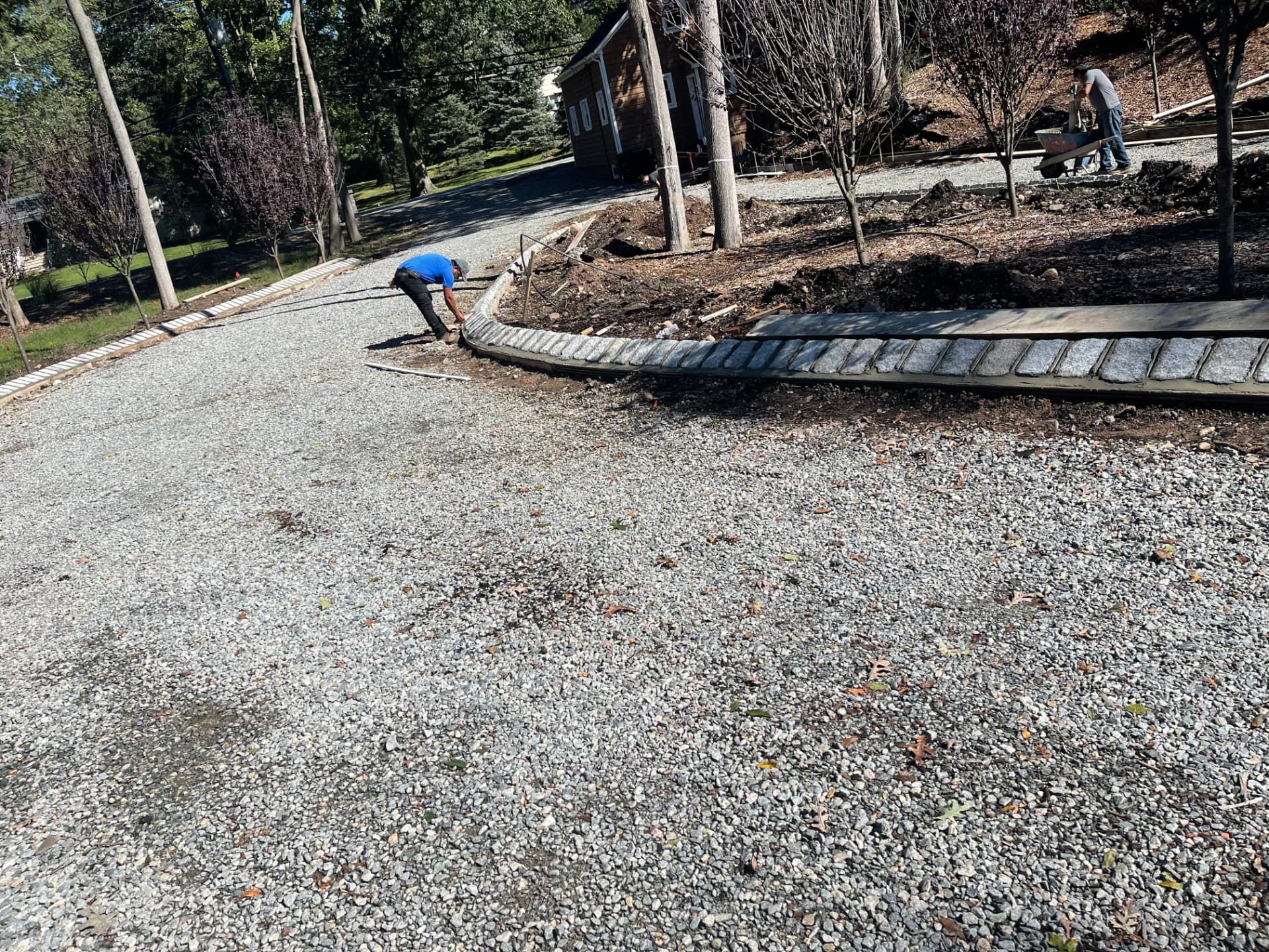 Crew installing granite cobblestone curbing along a driveway