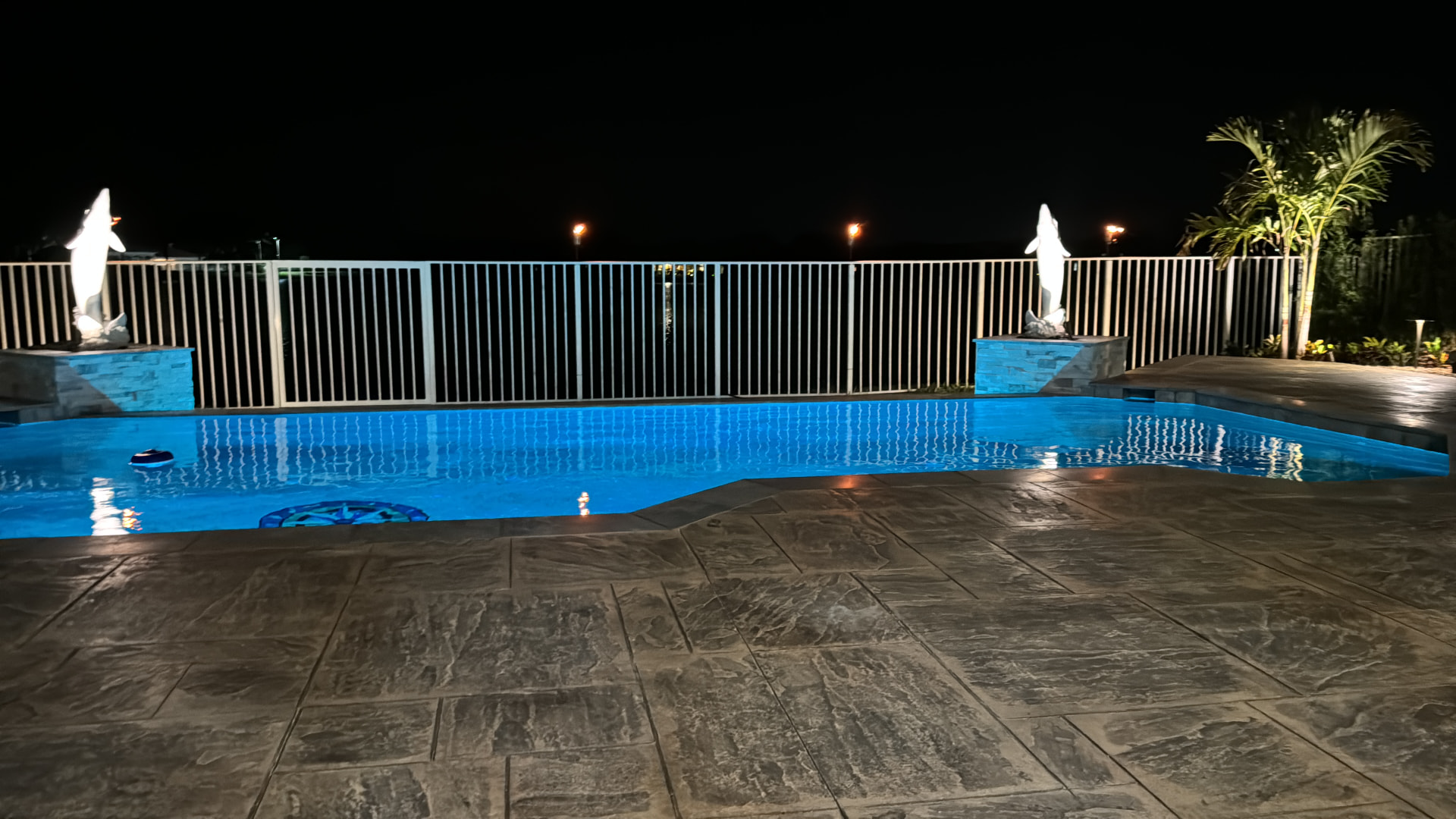 Stamped concrete pool deck lit at night